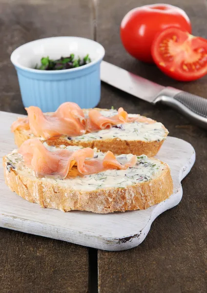 Fish sandwiches on cutting board on wooden table — Stock Photo, Image