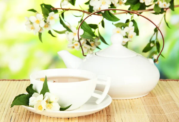 Cup of tea with jasmine, on bamboo mat, on bright background — Stock Photo, Image