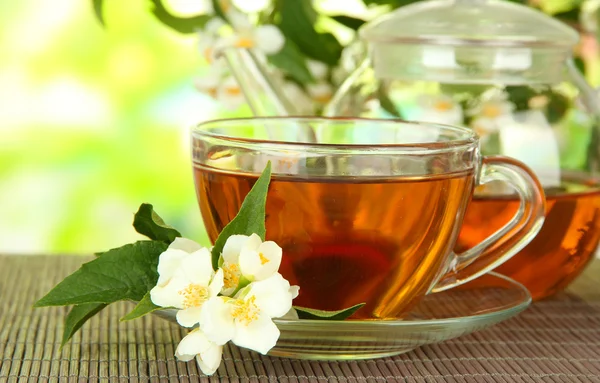 Taza de té con jazmín, sobre estera de bambú, sobre fondo brillante — Foto de Stock