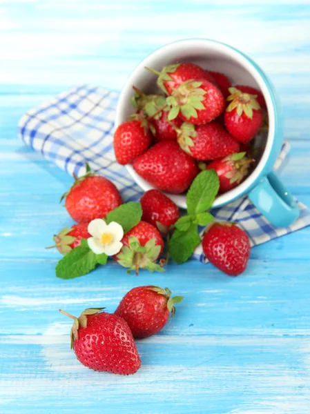 Fresas dulces maduras en taza sobre mesa de madera azul —  Fotos de Stock