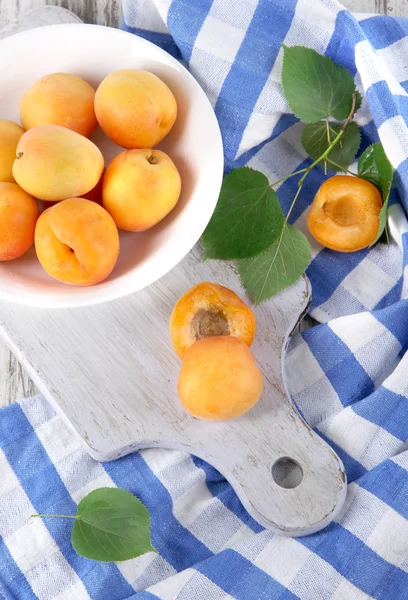 Apricots on board for cutting on napkin on wooden table — Stock Photo, Image