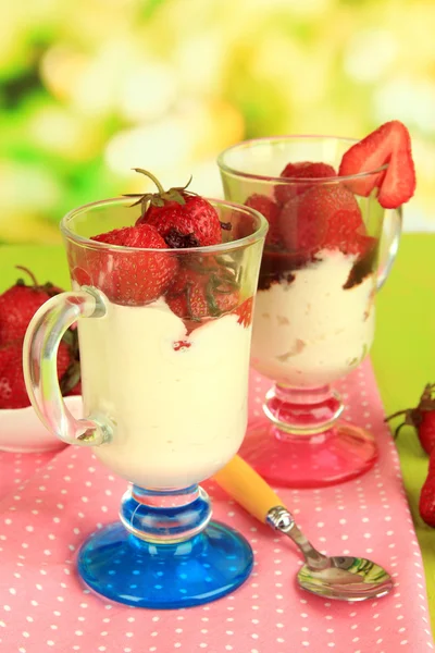 Deliziosi dessert alla fragola in vaso di vetro su tavolo di legno su sfondo naturale — Foto Stock