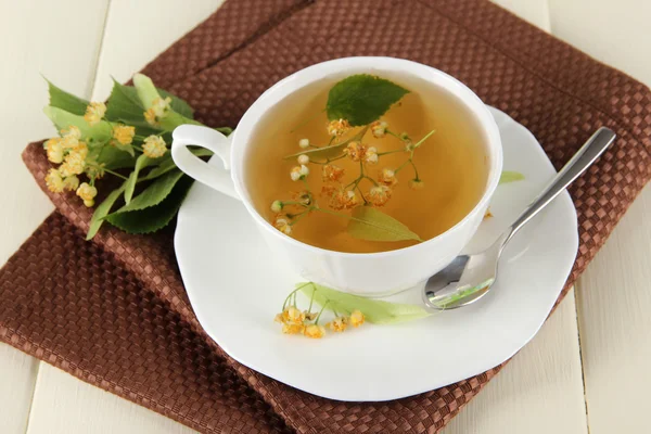 Kopje thee met linden op servet op houten tafel — Stockfoto