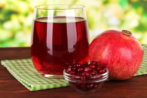 Glass of fresh garnet juice on table on bright background — Stock Photo, Image