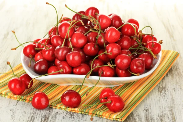 Bayas de cereza en el plato en la mesa de madera de cerca — Foto de Stock