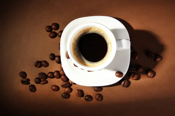 Kahverengi arkaplanda kahve çekirdeği olan bir fincan kahve. — Stok fotoğraf