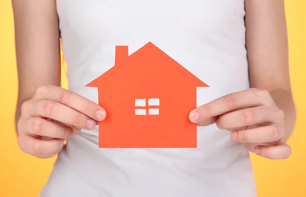 Paper house in hands on orange background — Stock Photo, Image