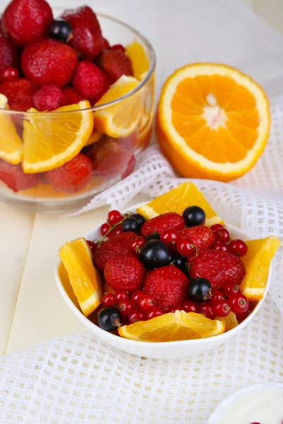 Useful fruit salad in glass cup and bowl on wooden table close-up — Stock Photo, Image