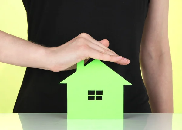 Papierhaus in der Hand auf grünem Hintergrund — Stockfoto