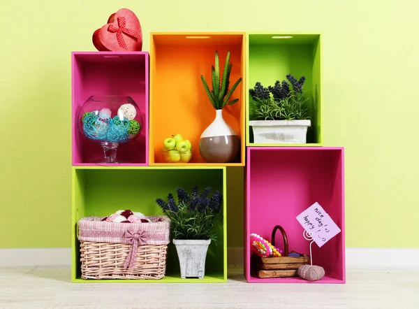 Schappen van verschillende heldere kleuren met decoratieve toevoeging op muur achtergrond — Stockfoto