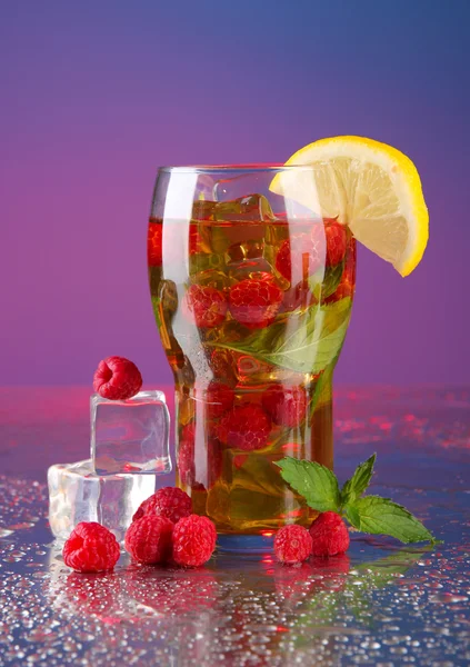 Iced tea with raspberries and mint on blue background — Stock Photo, Image