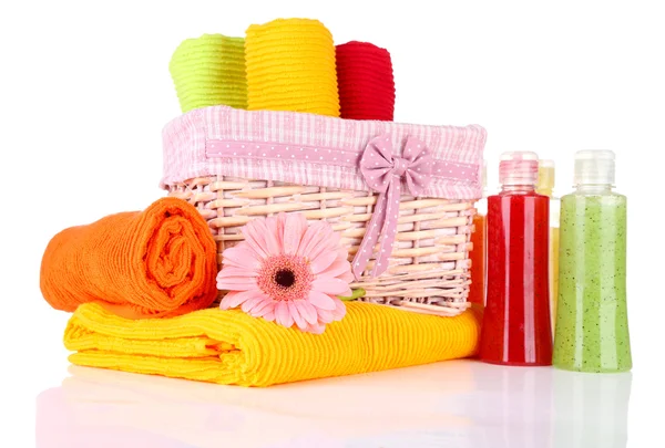 Красочные полотенца в корзине и косметические бутылки, изолированные на белом — стоковое фото