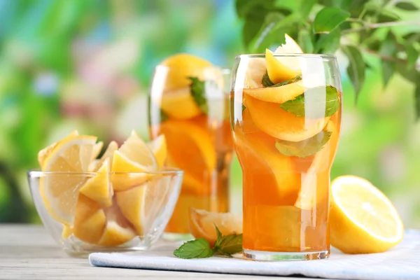 Té helado con limón y menta en la mesa de madera, al aire libre — Foto de Stock