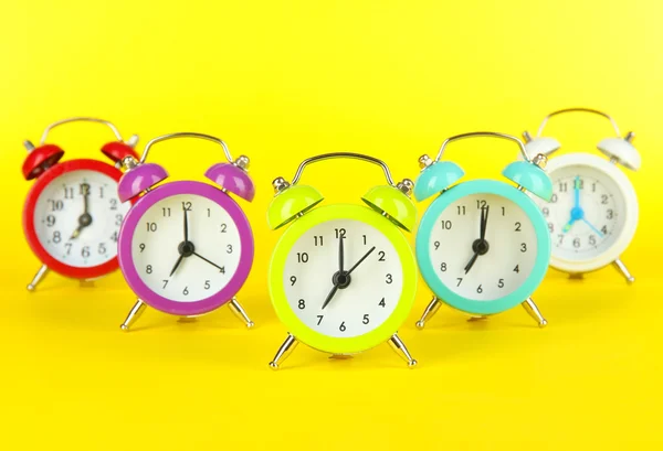 Reloj despertador colorido sobre fondo amarillo — Foto de Stock