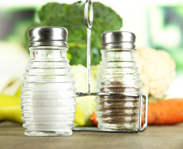 Salt and pepper mills, on wooden table, on bright background — Stock Photo, Image