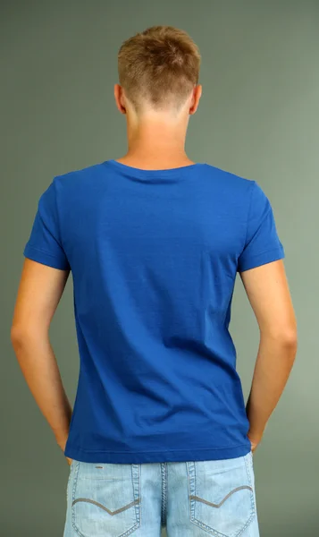 T-shirt op jonge man, op de grijze achtergrond — Stockfoto