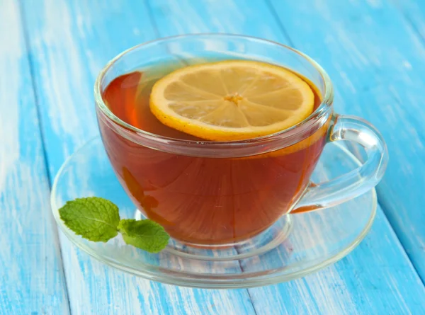 Šálek čaje s citronem na tabulce na modrém pozadí — Stock fotografie