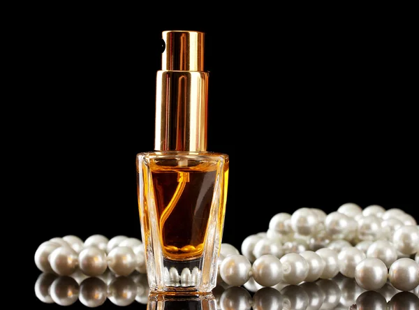 Women's perfume in beautiful bottle and beads, on black background — Stock Photo, Image