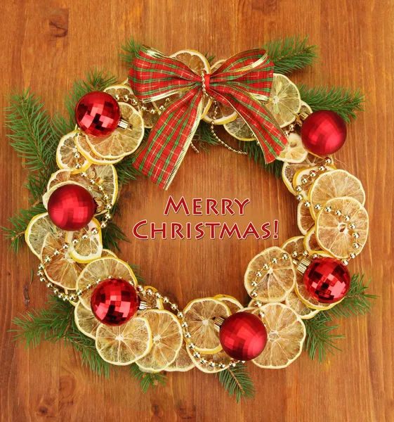 Christmas wreath of dried lemons with fir tree and balls, on wooden background — Stock Photo, Image