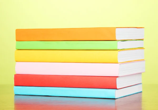 Stapel multicolor boeken op groene achtergrond — Stockfoto