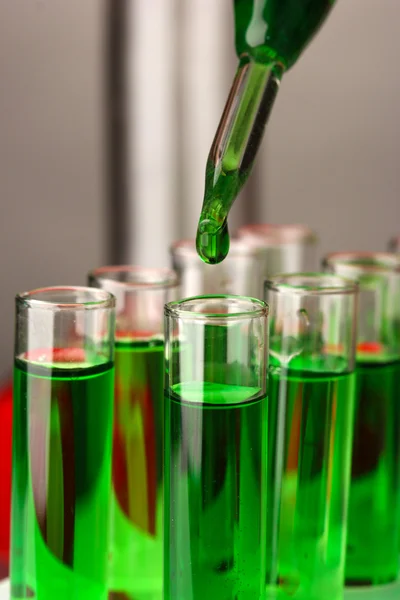 Laboratóriumi pipetta, színes folyadék felett üvegcsövekből, közelről — Stock Fotó