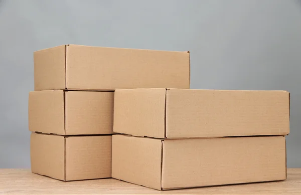 Parcels boxes on wooden table, on grey background — Stock Photo, Image