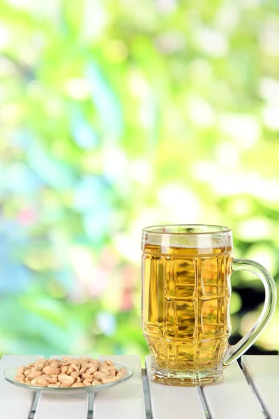 Beer in glass and nuts on table on nature background — Stock Photo, Image