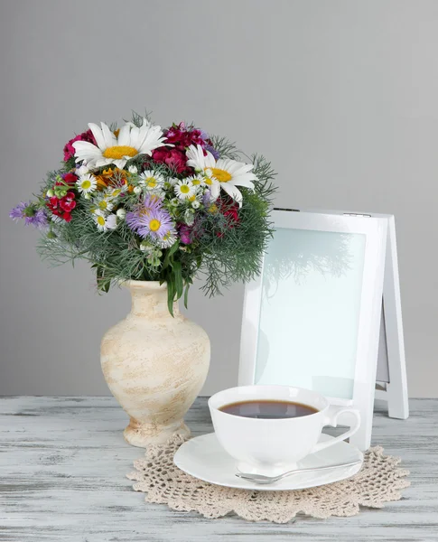 Mooie heldere bloemen in vaas op tafel op grijze achtergrond — Stockfoto