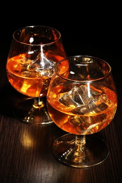 Copas de brandy con hielo sobre fondo de madera — Foto de Stock