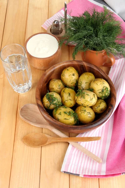 Boiled potatoes on wooden bowl near napkin on wooden table — Stock Photo, Image