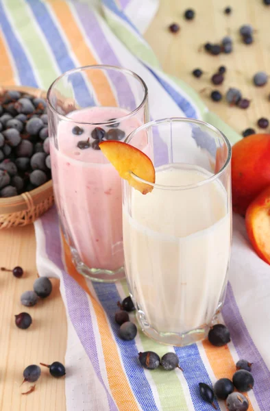 Pyszne koktajle mleczne z blackberry i brzoskwinia na drewniany stół szczegół — Zdjęcie stockowe