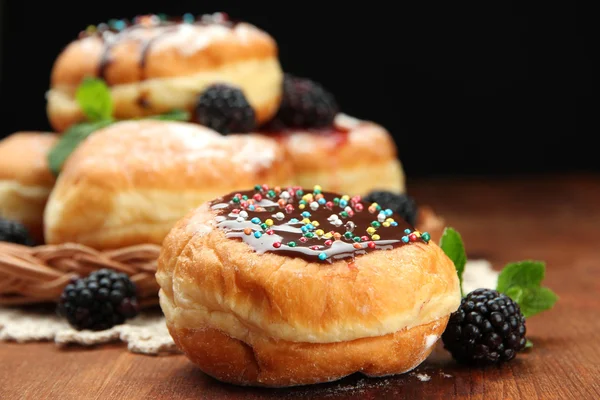 Tasty donuts with chocolate and berries on wooden table — Stock Photo, Image