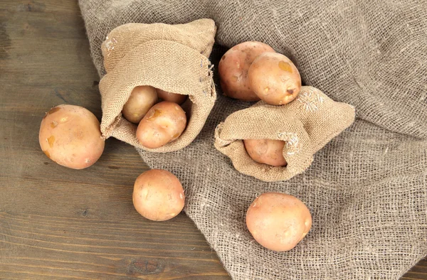 Картофель в мешках на мешке, на деревянном столе — стоковое фото