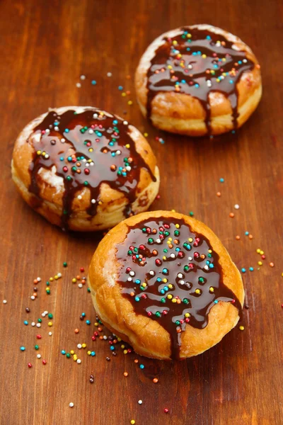 Donuts savoureux au chocolat sur table en bois — Photo