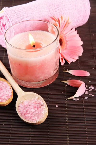 Beautiful pink candle with flower and towel on bamboo mat — Stock Photo, Image