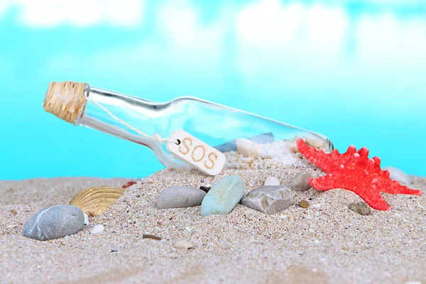 Glass of bottle with note inside on bright blue background — Stock Photo, Image