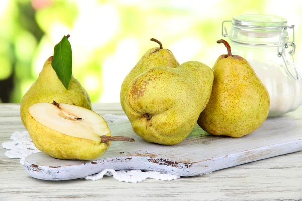 Pears on board on napkin on wooden table on nature background — Stock Photo, Image