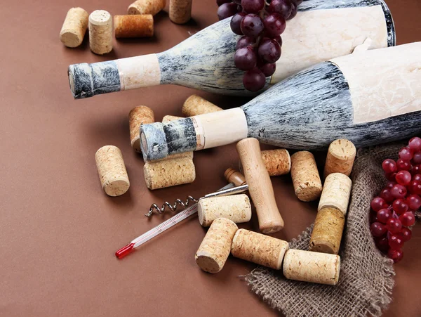 Old bottles of wine, grapes and corks on brown background — Stock Photo, Image