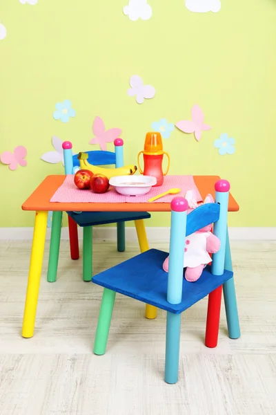 Вкусное детское фруктовое пюре и детская бутылка на столе в комнате — стоковое фото