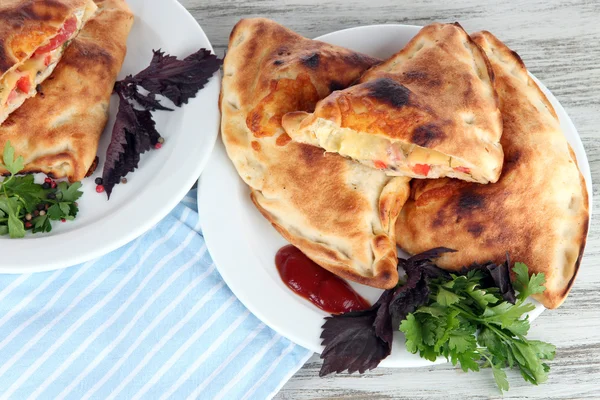 Pizza calzones op platen op servet op houten tafel — Stockfoto