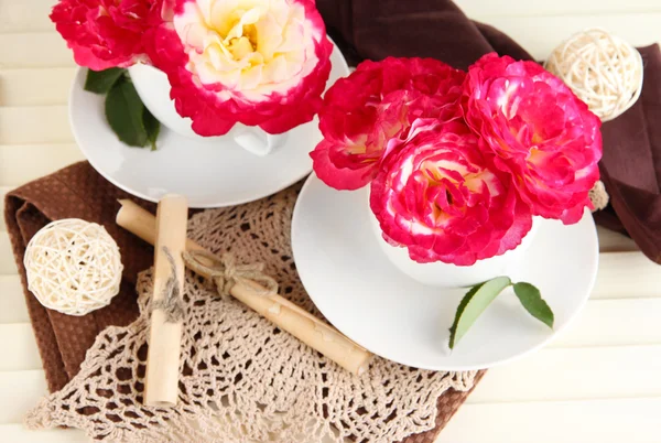 Rosas en tazas sobre servilletas sobre fondo de madera —  Fotos de Stock