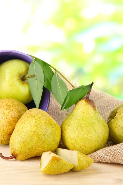 Pears in bucket on burlap on wooden table on nature background — Stock Photo, Image