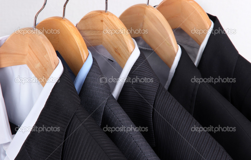 Suits with shirts on hangers on light background