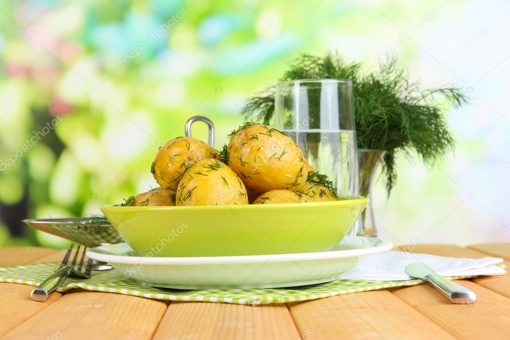 Boiled potatoes on platens on on napkins on wooden table on window background