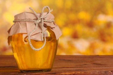 Jar of honey on wooden table on yellow background clipart