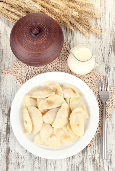 Tasty dumplings with fried onion on white plate, on wooden background — Stock Photo, Image