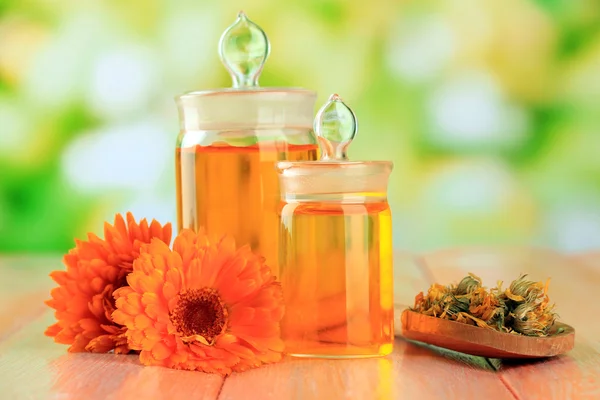 Medicine bottles and calendula flowers on wooden table — Stock Photo, Image