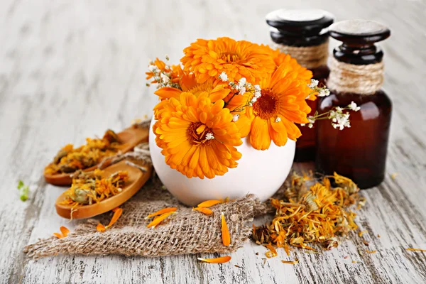 Bottiglie di medicina e fiori di calendula su sfondo di legno — Foto Stock