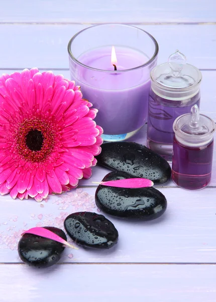 Piedras de spa, hermosa gerbera y vela sobre mesa de madera — Foto de Stock