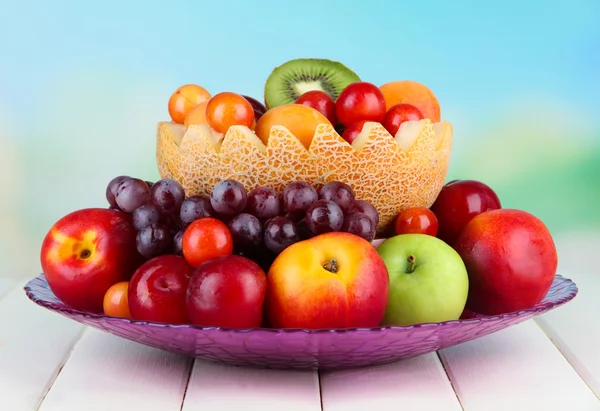 Assortment of juicy fruits on wooden table, on bright background — Stock Photo, Image